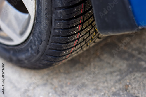 A stack of new all season tires against the background of a passenger car, illustrating tire replacement in autumn or spring and all-season tires as an alternative to seasonal tires.
