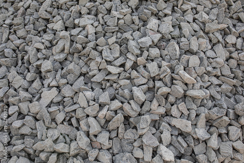 Texture of grey crushed granite stone gravel pile for construction industry and road building material background