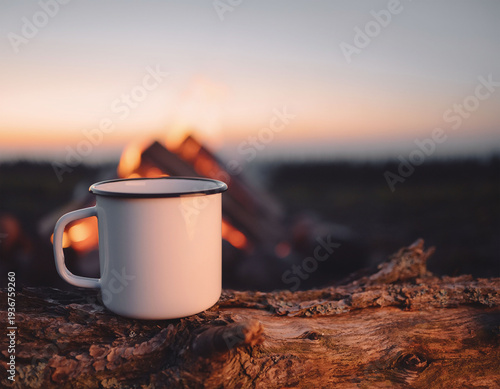 White enamel mug by campfire, hot drink outdoors camping
