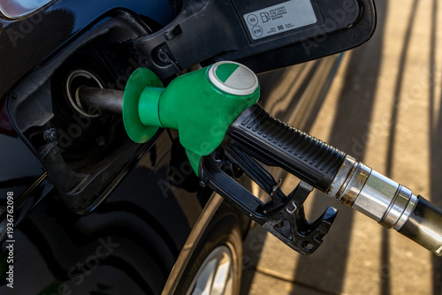 Quadro su tela Green fuel dispenser inserted into the fuel filler of a car, filling up a car, r