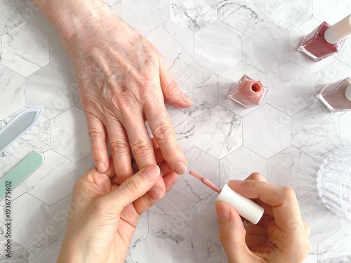 Senior woman receiving manicure nail care at beauty salon close up