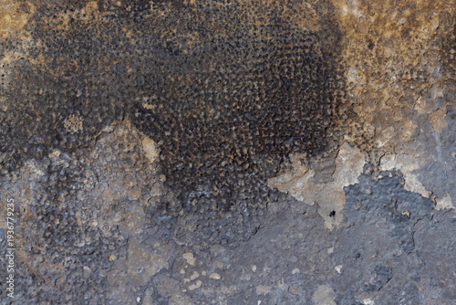 Close-up of an aged concrete wall showing peeling paint, rust stains and text...