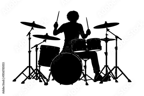 Silhouette of young male drummer playing drum set.
