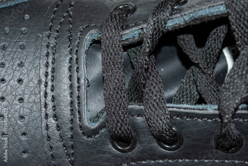 Detalle de cordones enlazados en zapatillas deportivas de color negro.