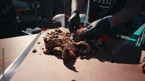 Bird's eye overhead view of shredded pulled pork spread across pink butcher paper in a metal tray with visible charred ends and juices