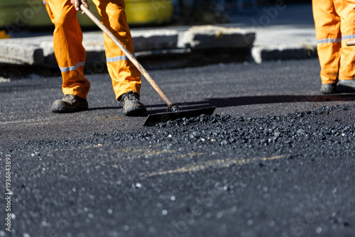 Road construction worker leveling asphalt during paving
