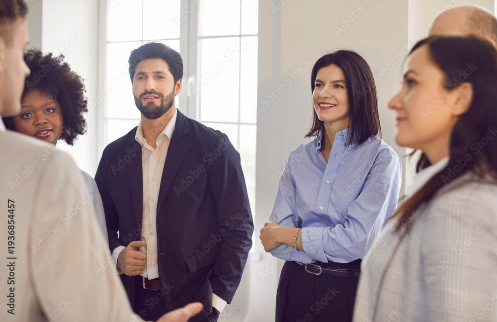 Fototapeta premium Portrait of a group of young confident diverse business people standing in office discussing job project or startups. Coworkers and company employees talking with colleague on a meeting.