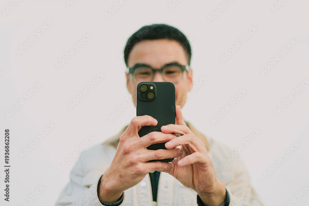 Fototapeta premium adult asian man using mobile, cell phone.portrait young male person posing smart phone smiling laughing look fun excited surprised happy.empty space for text advertising