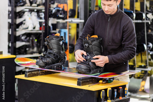 Snowboard Boots for Rent. Worker Adjust Bindings in Ski Rentals Center. Technician Adjusting Snowboard Boots Before Riding. Snowboard Equipment Fitting at Ski Center. 