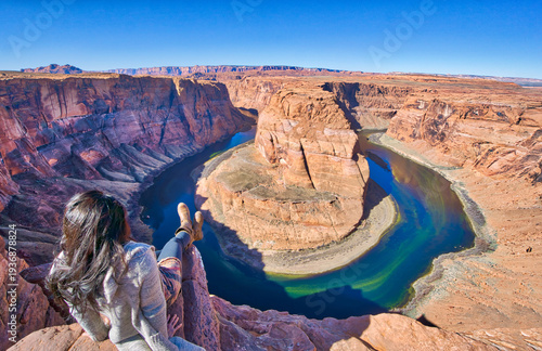 A woman is sitting on a rock overlooking a river