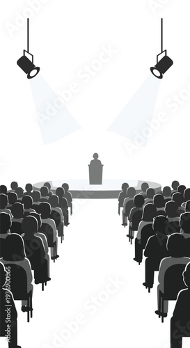 A speaker stands at a podium on a raised stage, illuminated by two spotlights, addressing a large audience of silhouetted figures.