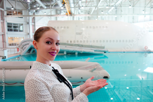 Female aviation professional demonstrating aircraft emergency ditching training in airline safety training facility with rescue equipment and aircraft mockup, concept of aviation career, safety 