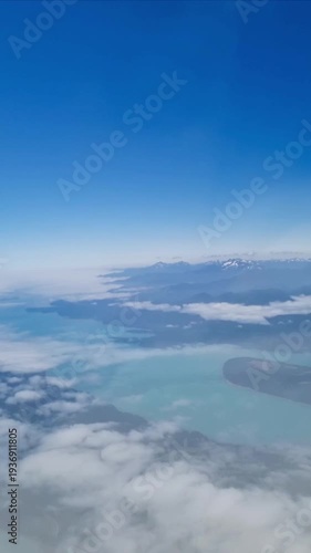 Wallpaper Mural Aerial view of coastline, lakes and mountains seen from airplane above clouds. Scenic landscape with blue sky and water during flight, travel and tourism concept. Torontodigital.ca