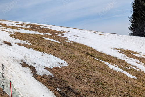 Melting snow reveals brown grass on a ski slope in Sugadaira, Nagano, Japan in spring
