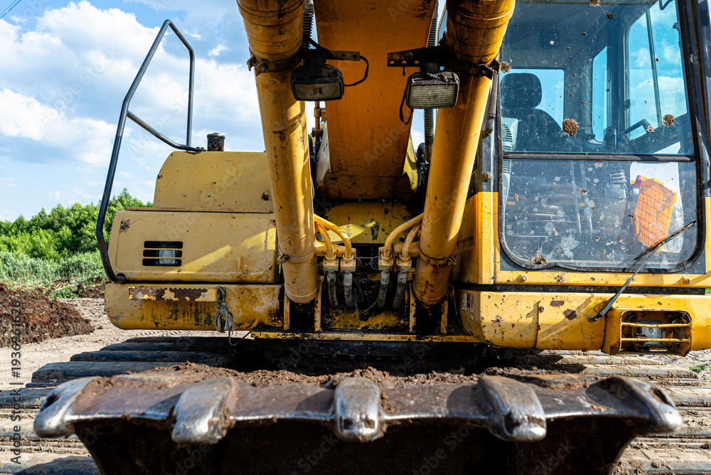 Fototapeta premium Yellow excavator bucket and cabin showing heavy construction equipment
