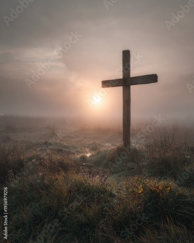 A lonely wooden cross in a field covered in thick morning mist. 