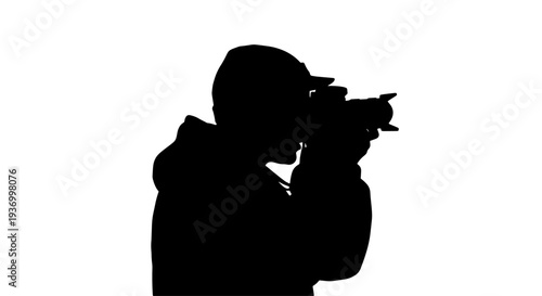 A silhouette of a photographer holding a camera, capturing a moment against a bright white background.