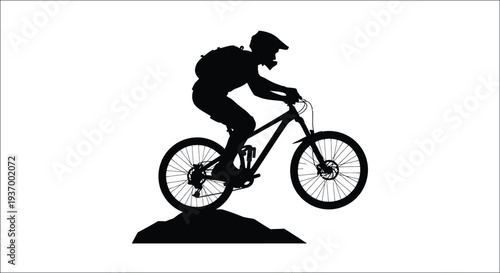 Silhouette of a mountain biker riding uphill on a dirt trail