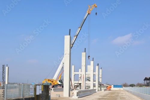 Wallpaper Mural Mobile crane installing main pillars of the  prefab industrial building under construction. Blue sky with clouds on background Torontodigital.ca