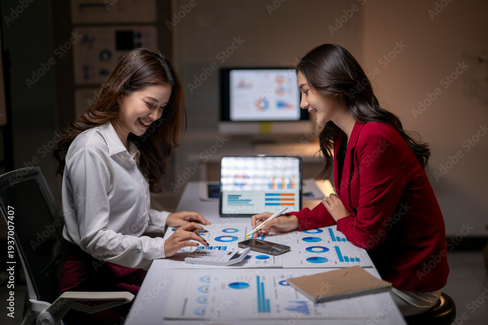 Fototapeta premium Businesswomen analyzing financial data in office at night
