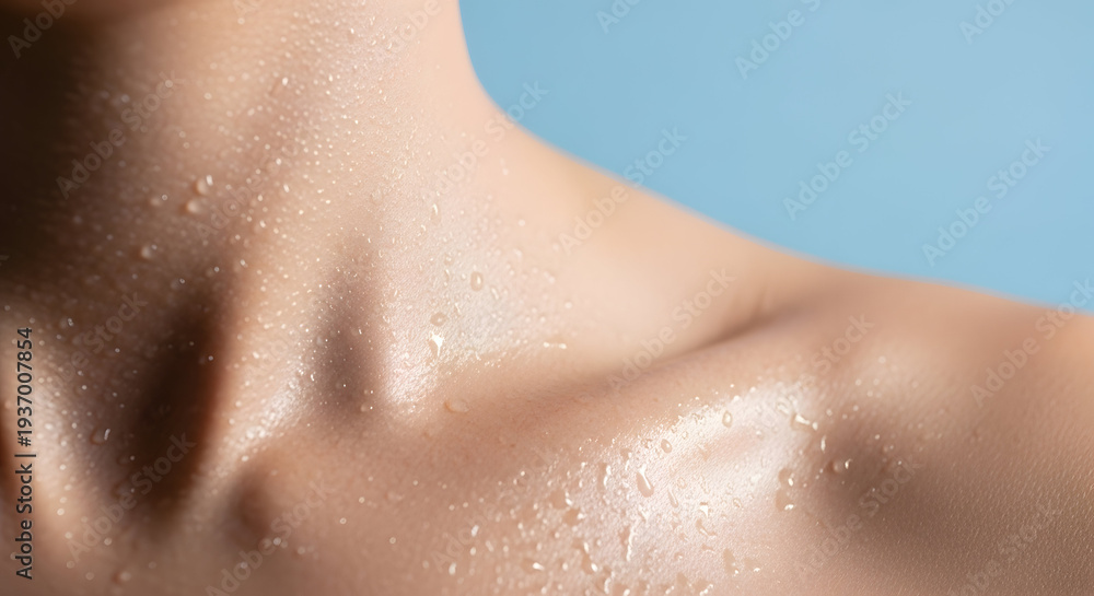 Fototapeta premium Close up of a person's neck and shoulder with water droplets on the skin against a soft blue background highlighting skin texture and hydration
