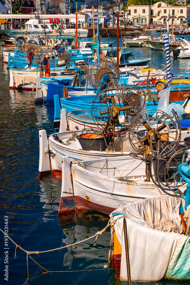 Fototapeta premium Colorful fishing boats in the harbor of Capri (Marina Grande, Italy). Summer atmosphere with sunny weather at a popular tourist destination, jet-set retreat, and dream location in the Mediterranean. 