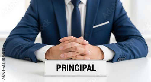 Principal sitting at a table with the word Principal on a nameplate