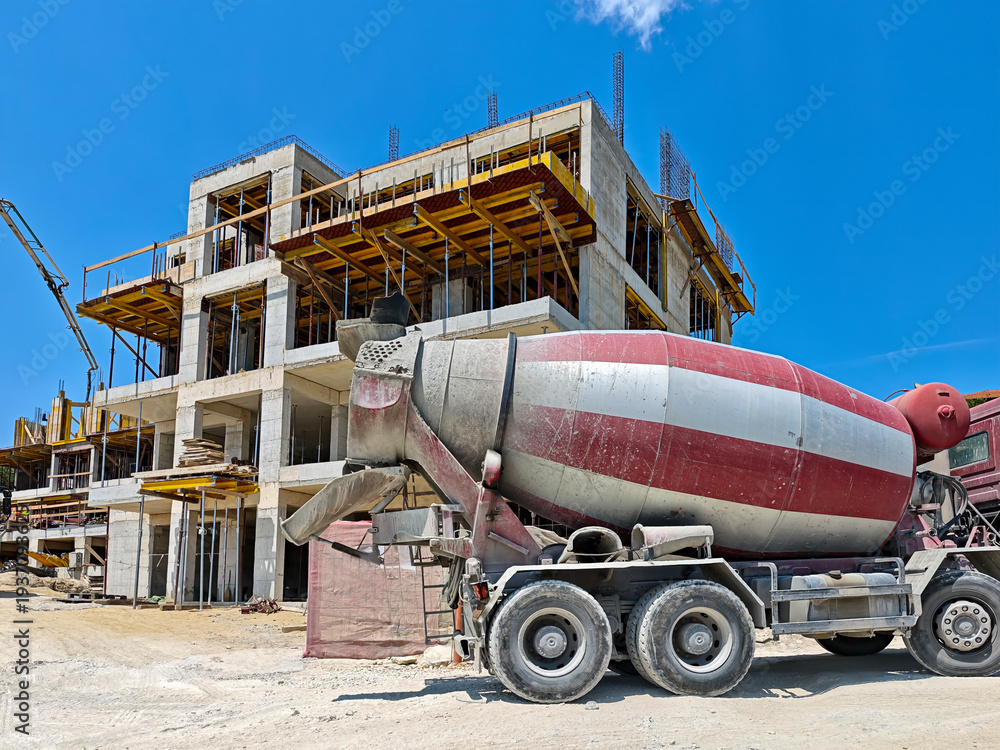 Naklejka premium Large concrete mixer truck on a construction site. Concept of real estate, architecture, and urban development.