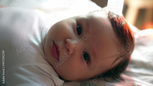 Fotografia Baby lying on bed with soft gaze, peaceful and content expression, early develop