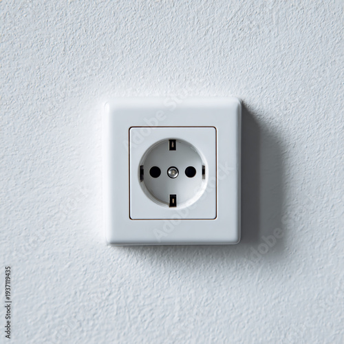 A white European-style electrical outlet mounted on a textured light gray wall.