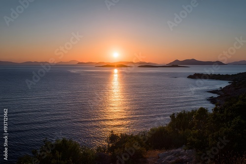 The sun sets over the ocean, casting a golden glow on the water