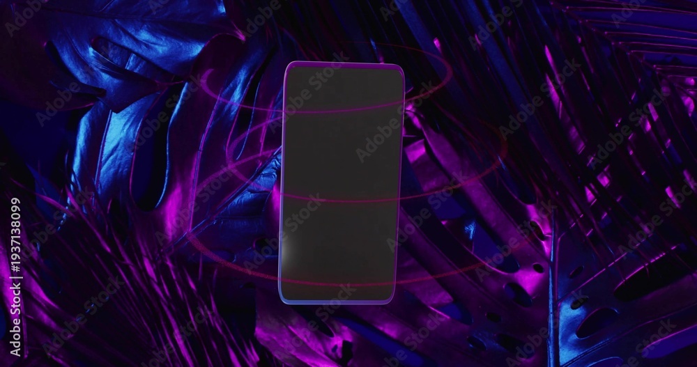 Fototapeta premium Floating smartphone hovering above glossy tropical leaves in studio, neon rings circling