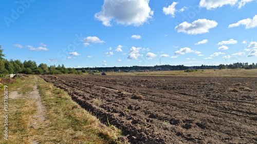 Fotografia A tractor with plows plows an agricultural field after harvesting