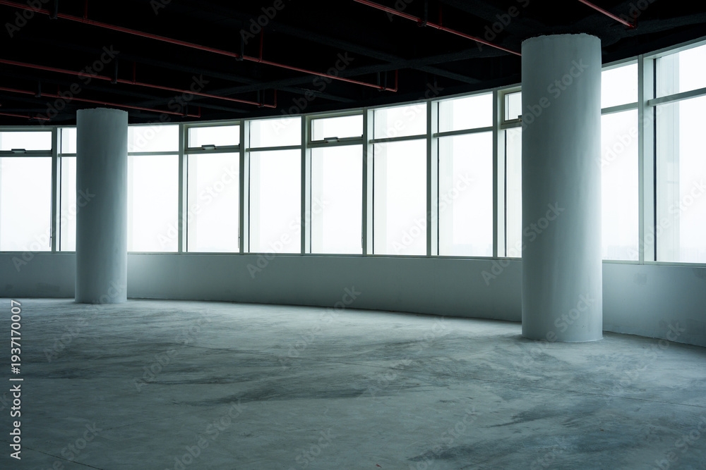 Fototapeta premium Spacious empty office interior with floor-to-ceiling windows and concrete columns