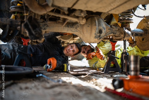 фотографія Mechanics working together inspecting car undercarriage for repair