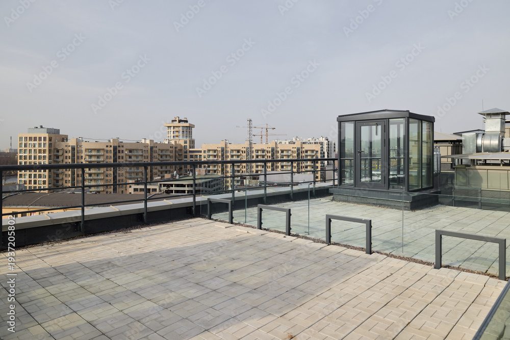 Fototapeta premium Spacious urban rooftop with glass elevator and skyline vista