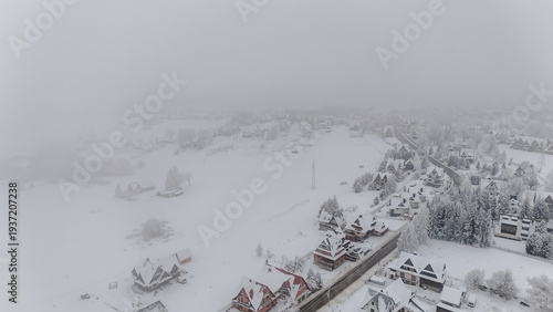 Aerial View of Snow-Covered Mountain Village with Chalets in Winter Fog – European Resort Town