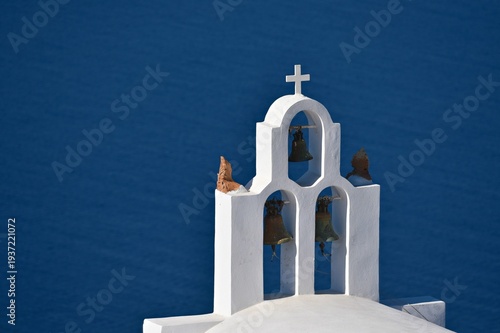 Tableau sur toile Landscape with scenic view of a typical Greek Orthodox church arched campanile with a white marble cross overlooking the Aegean Sea in Santorini, Cyclades Greece