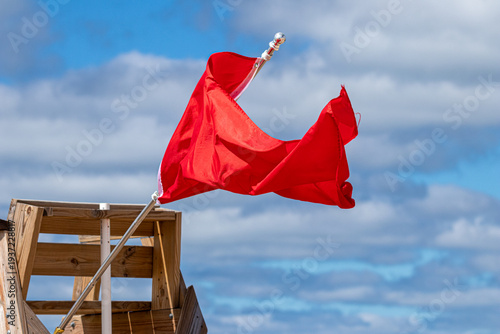 Red flag on a lifeguard chair waving in the wind with copy space 