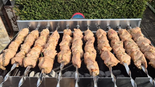 The kebabs are grilled on the coals while rotating.