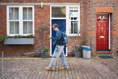 Fotografía Man in casual clothing and backpack walking on a historic london street, focusin