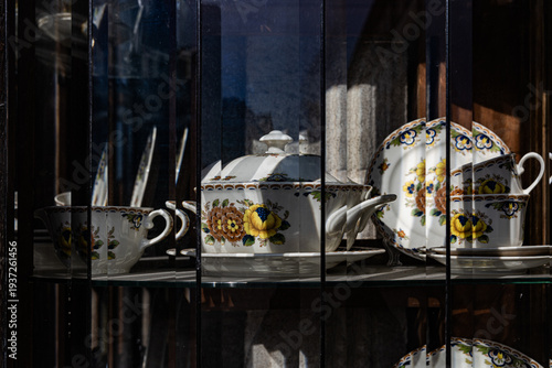 Obraz na plátne Vintage Floral Porcelain Tea Set Behind Fluted Glass Showcase