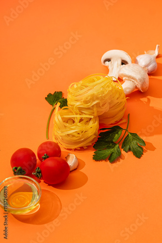 Food ingredients for cooking Italian pasta. Fresh cherry tomatoes, mushrooms, garlic, parsley, olives, spaghetti, olive oil on orange background top view