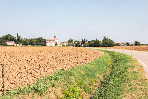 Fotografija Via Francigena - a paved road through plowed agricultural fields near Paderna, c