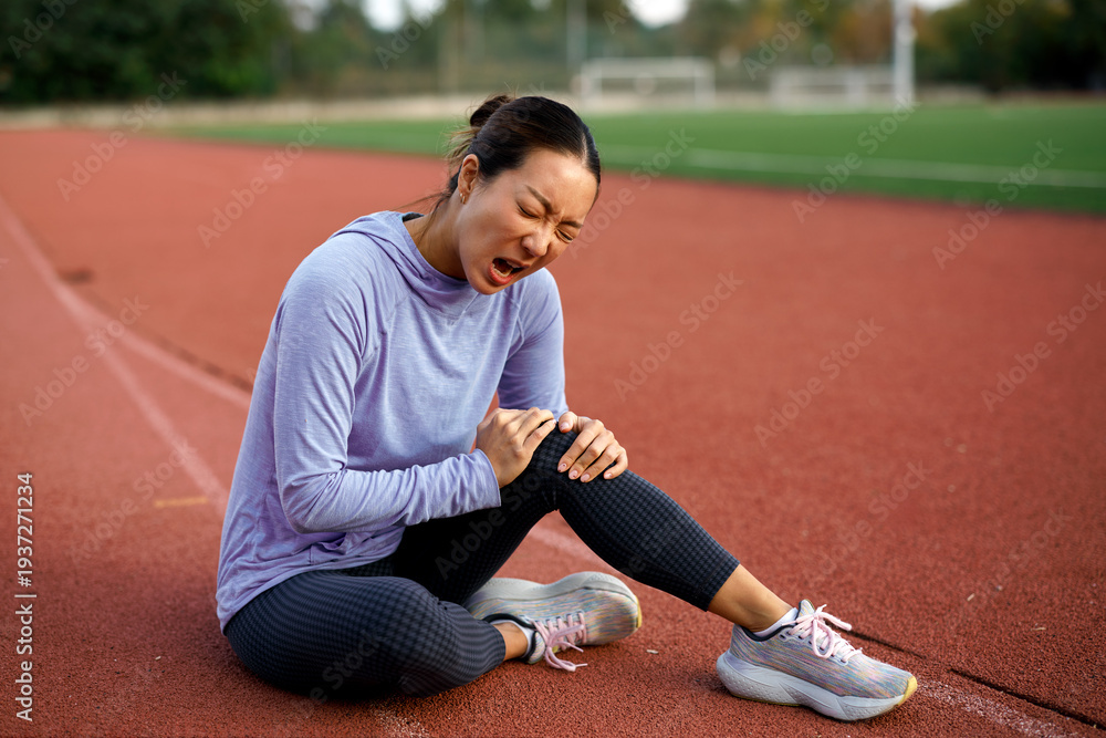 Naklejka premium Female athlete feeling knee pain after outdoor workout