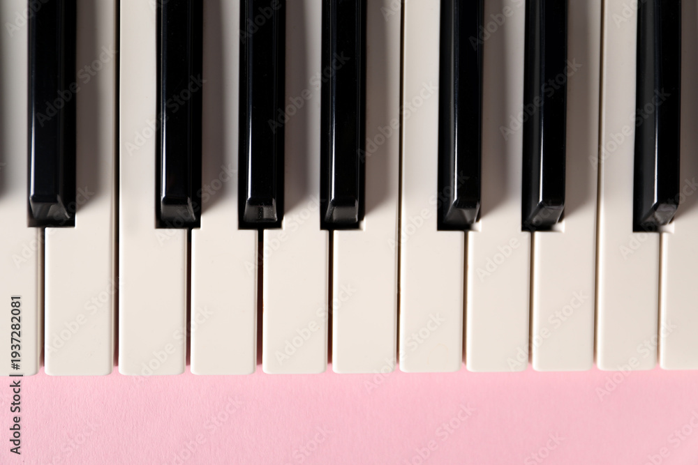 Naklejka premium Piano keys on pink background, top view. Musical instrument