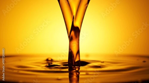 Golden liquid stream pouring into a reflective pool, creating ripples and a vibrant background.