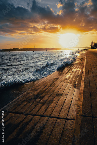 Golden sunset over ocean waves and seaside promenade