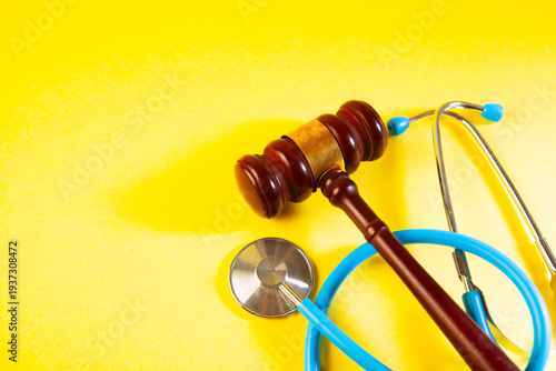 stethoscope and rubber gavel on yellow background