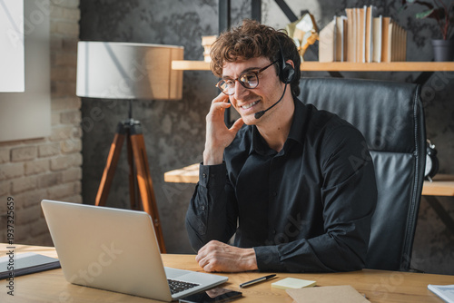 Obraz na płótnie Enthusiastic businessman in headset, video calling at workplace
